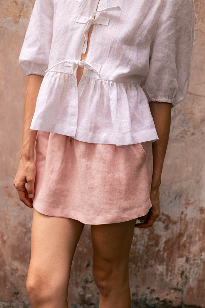 Woman wearing summery the label's classic linen skirt in dusty pink
